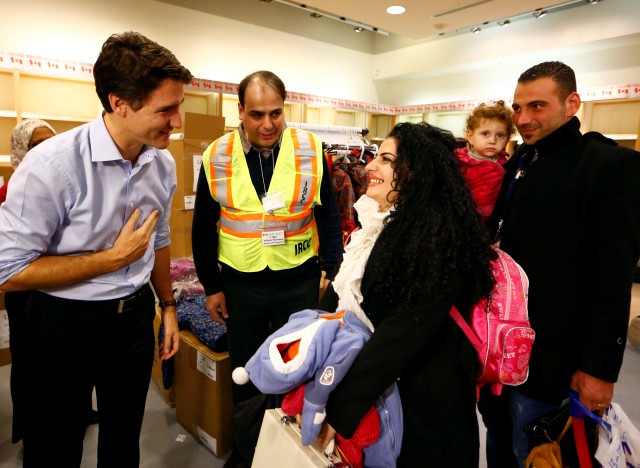 Syrian refugees are greeted by Canada's Prime Minister Justin Trudeau (L) on their arrival from Beirut at the Toronto Pearson International Airport in Mississauga, Ontario, Canada December 11, 2015. After months of promises and weeks of preparation, the first Canadian government planeload of Syrian refugees landed in Toronto on Thursday, aboard a military aircraft met by Prime Minister Justin Trudeau.  REUTERS/Mark Blinch TPX IMAGES OF THE DAY - RTX1Y6RP
