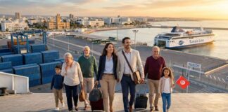 Fuite des cerveaux : Pourquoi les compétences tunisiennes envisagent-elles de quitter l’Europe ? Photographie aérienne d'une famille multigénérationnelle de la diaspora (6 personnes) débarquant joyeusement d'un ferry dans le port de Tunis (La Goulette). Au premier plan, un couple qualifié tire des valises, un grand-parent est ému, et un enfant tient un drapeau tunisien. En arrière-plan, le grand ferry 'TUNISIA LINE' et les infrastructures portuaires sont éclairés par la lumière dorée du lever du soleil.