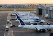 Transport Aérien : Nouvelair prend de l’altitude et dépasse Tunisair en flotte opérationnelle Vue aérienne au lever du soleil sur le tarmac de l'aéroport Tunis-Carthage. On y distingue clairement une rangée d'avions de la compagnie privée Nouvelair (livrée blanche et bleue, incluant le nouvel A320neo) alignés parallèlement à une rangée d'appareils Tunisair (livrée blanche avec la gazelle rouge).