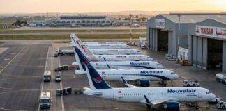 Transport Aérien : Nouvelair prend de l’altitude et dépasse Tunisair en flotte opérationnelle Vue aérienne au lever du soleil sur le tarmac de l'aéroport Tunis-Carthage. On y distingue clairement une rangée d'avions de la compagnie privée Nouvelair (livrée blanche et bleue, incluant le nouvel A320neo) alignés parallèlement à une rangée d'appareils Tunisair (livrée blanche avec la gazelle rouge).