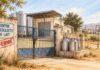 Filière laitière : cinq centres de collecte fermés à Sidi Bouzid Centre de collecte du lait fermé, portail cadenassé et bidons métalliques dans un paysage rural évoquant Sidi Bouzid