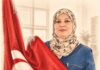 Amel Hamdi – fondatrice de Quatre A Energy : « Pour moi, l’énergie solaire doit être accessible, fiable et intelligible pour tous les Tunisiens » Portrait au crayon d’une femme tunisienne portant un hijab fleuri et tenant le drapeau national tunisien, sur fond ivoire.